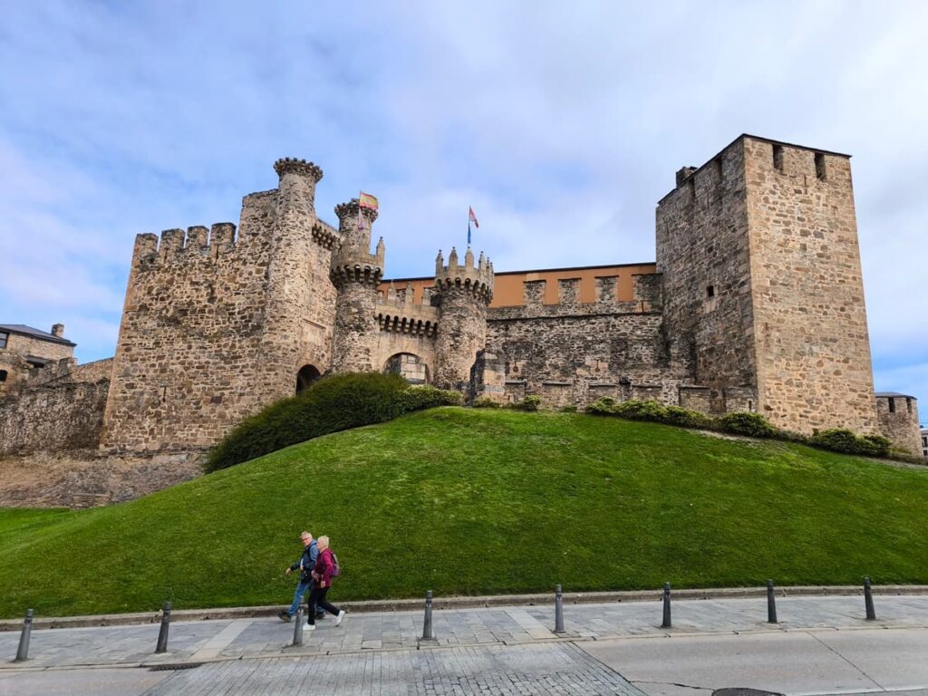 Dos peregrinos pasan frente al castillo de los templarios de Ponferrada
