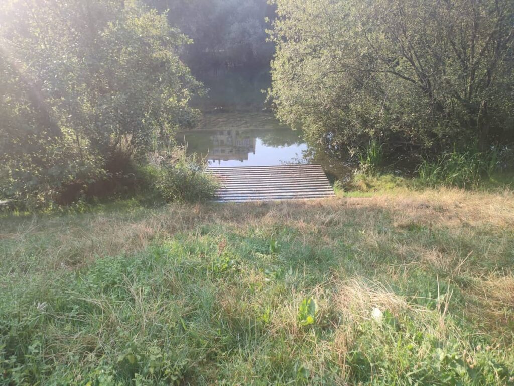 Embarcadero retirado junto a la orilla del río Sil en Ponferrada, rodeado de vegetación.