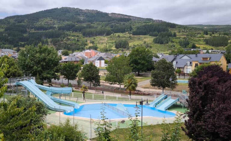 Piscinas de los toboganes de Vega de Espinareda, con el núcleo urbano y el entorno montañoso al fondo.