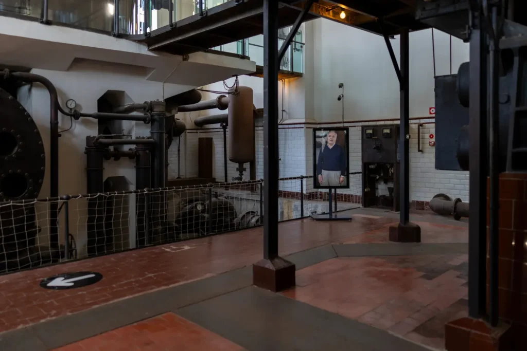 Interior de La Fábrica de Luz. Museo de la Energía, con maquinaria industrial, pasarelas y una pantalla dentro del espacio de la nave de turbinas.