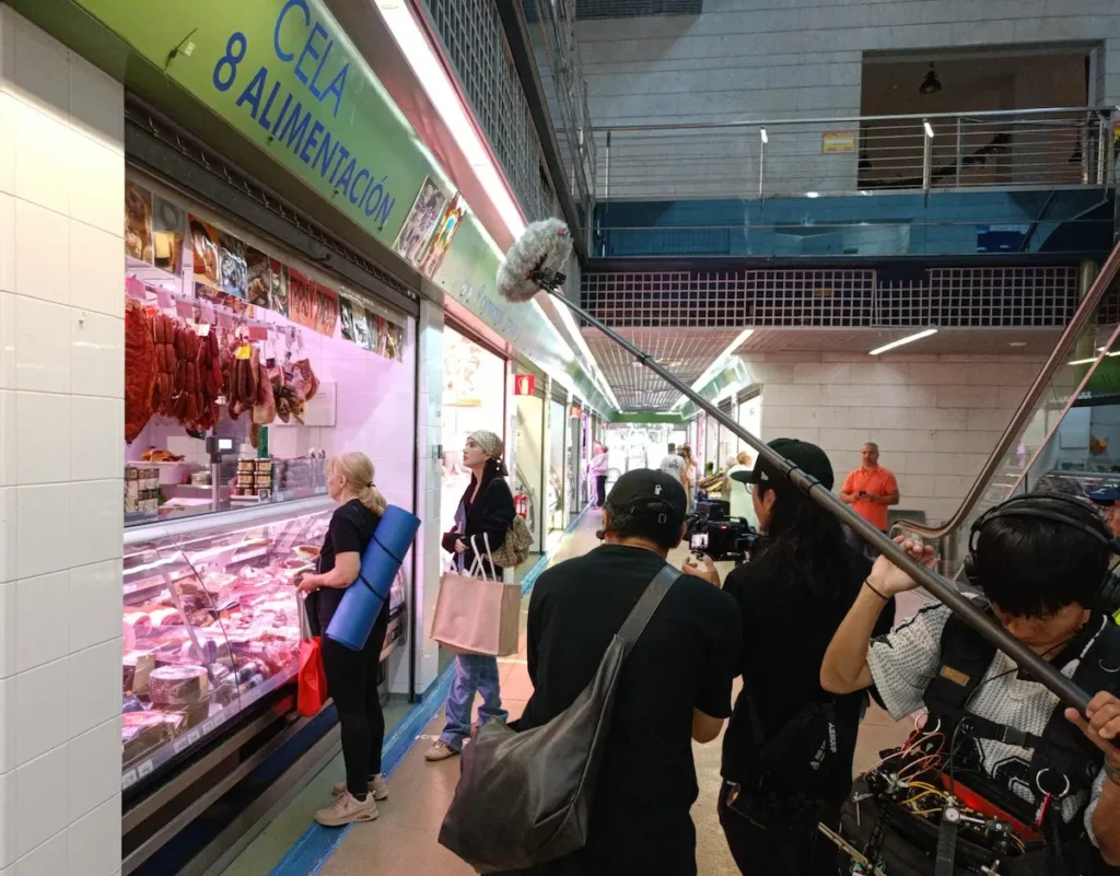 Rodaje del reality asiático What A Trip 2 en el Mercado de Abastos de Ponferrada, con una participante comprando productos locales.