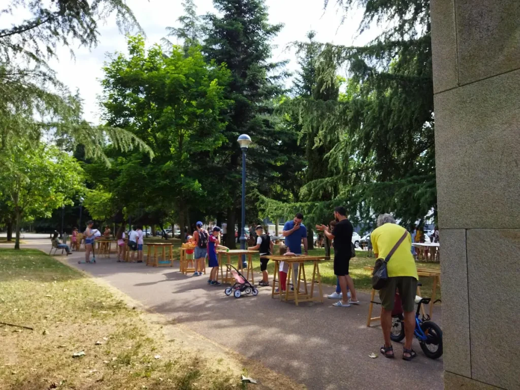 Familias y niños participan en actividades de educación ambiental al aire libre en una zona verde de Ponferrada.