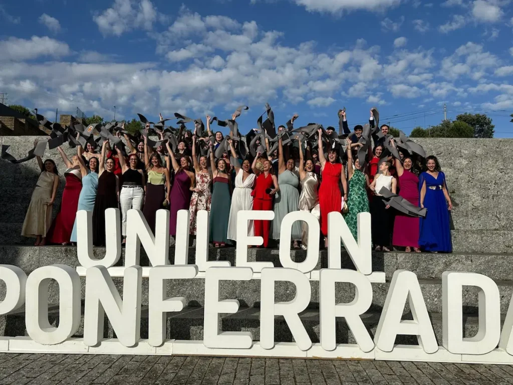 Estudiantes de Enfermería del Campus de Ponferrada celebran su graduación lanzando las becas junto a las letras de la Universidad de León.