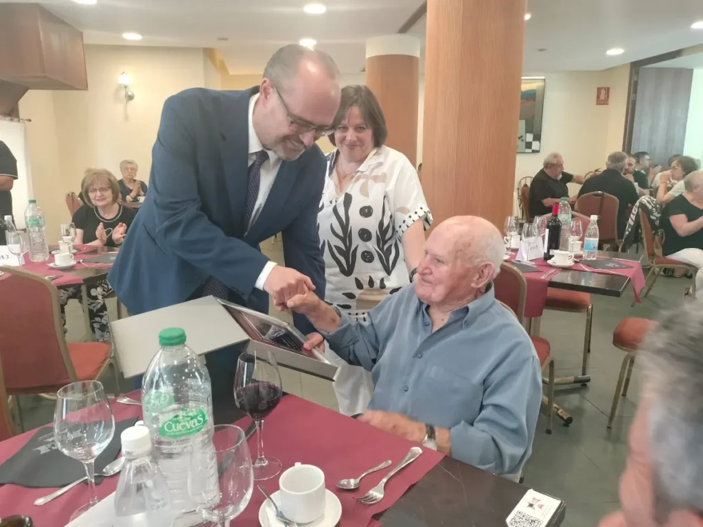 Representantes municipales de Ponferrada entregan una placa conmemorativa a un usuario centenario de los Centros de Día durante un homenaje celebrado en la ciudad.
