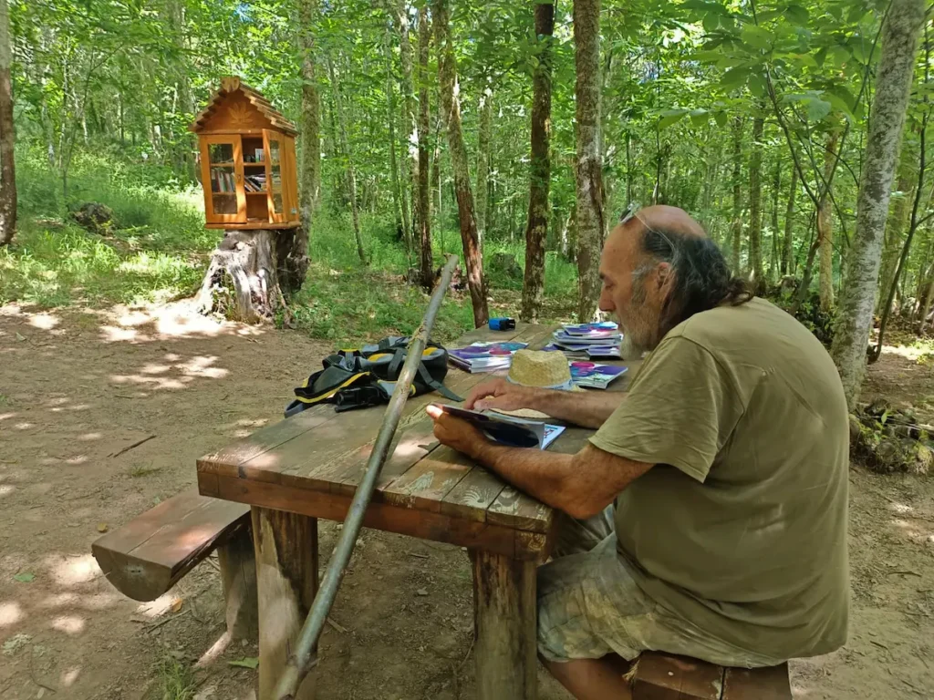 Minibiblioteca del Soto de Villar de los Barrios instalada en un entorno boscoso con libros disponibles para el intercambio y la lectura al aire libre.