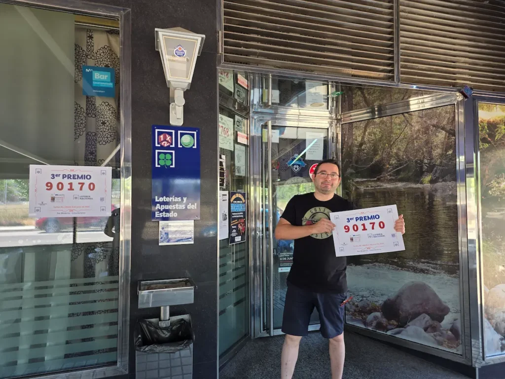 Responsable del Bar Moderno de Columbrianos muestra el cartel del tercer premio de la Lotería Nacional vendido en el establecimiento.