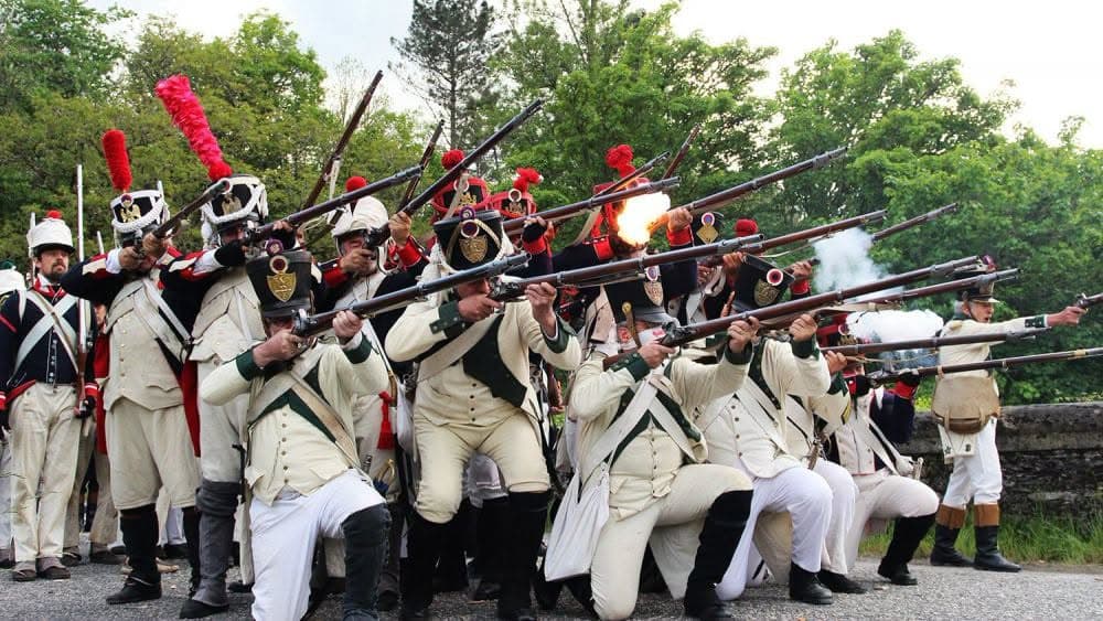 Recreadores históricos caracterizados como soldados de los ejércitos napoleónicos realizan una descarga de fusilería durante una recreación de la Guerra de la Independencia en la III Jornada Napoleónica de San Pedro Castañero