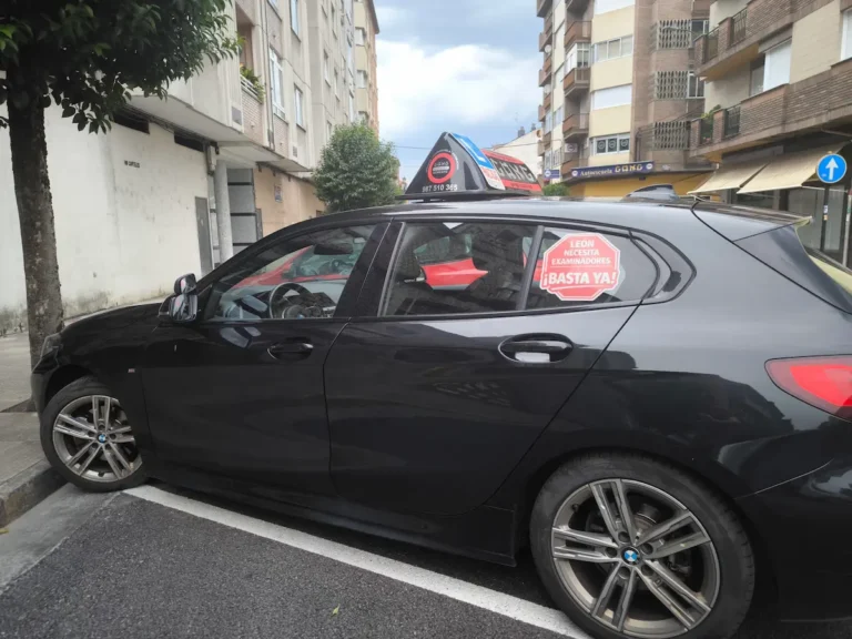 Vehículo de autoescuela con un cartel que reclama más examinadores de Tráfico para la provincia de León.