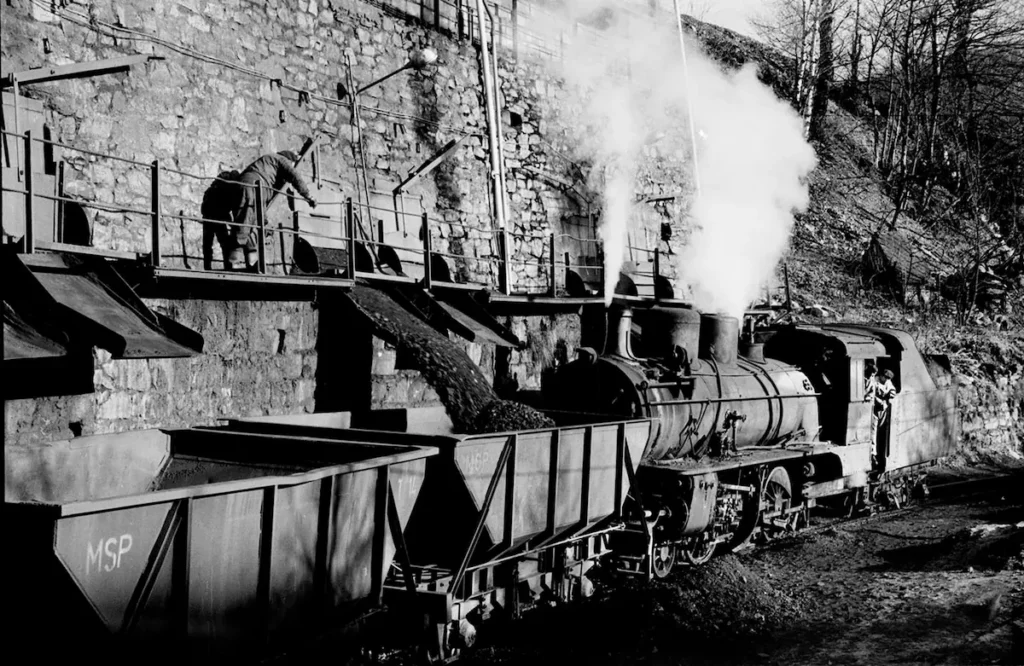Locomotora de vapor del tren minero Ponfeblino junto a varios vagones durante una operación de carga en Caboalles
