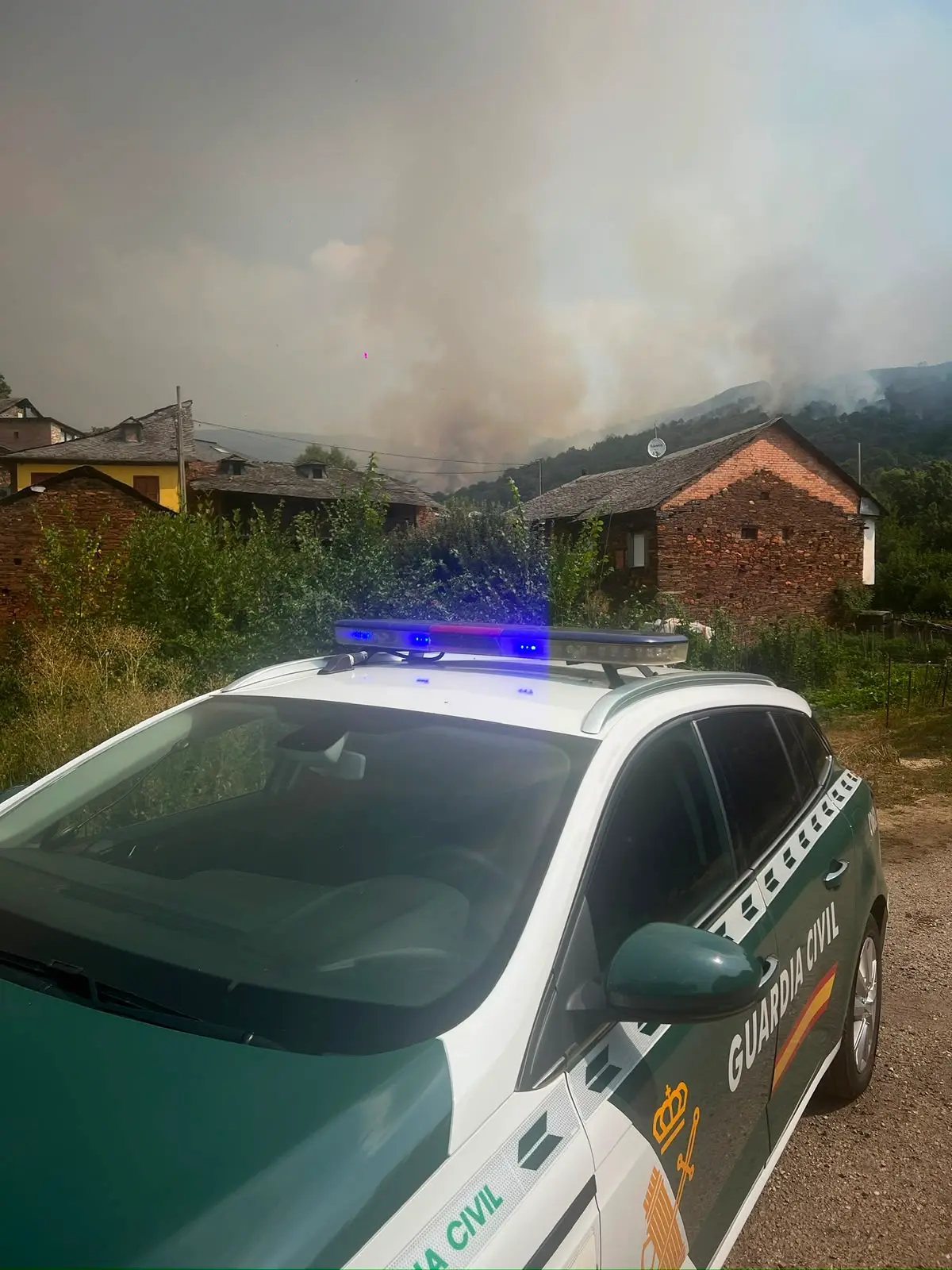 Vehículo de la Guardia Civil desplegado ante la columna de humo provocada por el incendio forestal de Veguellina.